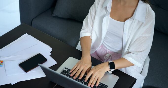 Female typing at desk. Lady composing report with devices nearby. Woman focused on writing report using multiple gadgets. Individual engaged in data entry in cozy home workspace setting