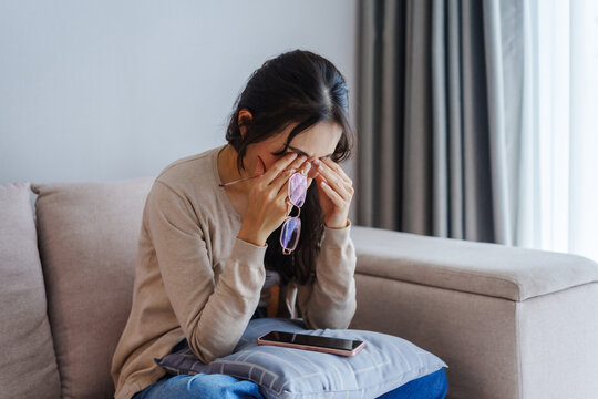 Young woman rubbing her eyes from using eyesight to relieve eye pain after using mobile phone