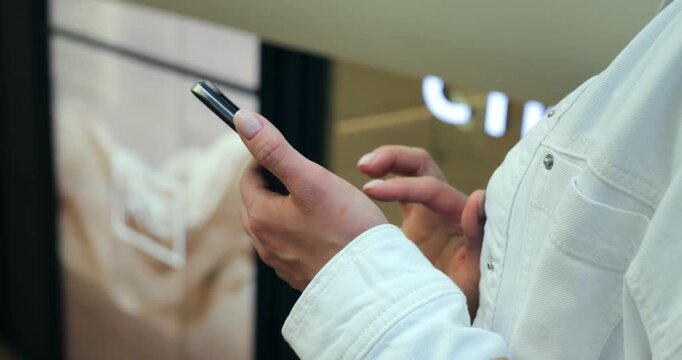 Closeup hands holding smartphone tapping screen. Casual person in white jacket interacting with touchscreen, composing message, scrolling social feed, checking notification, soft indoor lighting,