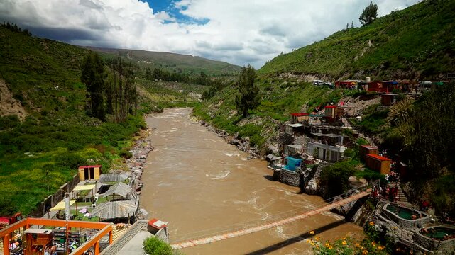 Scenic view of the muddy river flowing under a bridge at Banos Termales de Chacapi near Chivay in the Colca Canyon region of Peru, South America