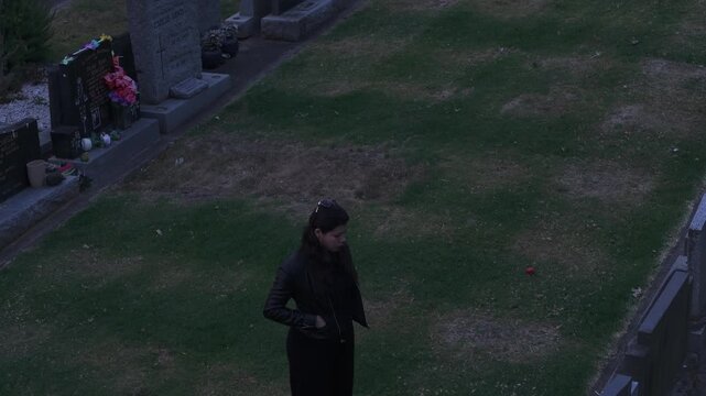 Dramatic jib angle lift capturing a woman in a Melbourne graveyard at sunset. The rich, moody lighting creates an introspective atmosphere, highlighting the tranquil scene.