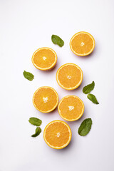 Fototapeta premium Fresh orange halves with mint leaves on light background