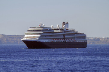 Luxury cruiseship cruise ship liner Eurodam anchoring at sea on sunny summer day during Mediterranean Greek Island Santorini caldera cruising with shore and rocky island in background © Tamme Wichmann
