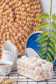 Rainbow Putri Salju cookie  with a sprinkling of white powdered sugar in a jar, served with a cup of tea.