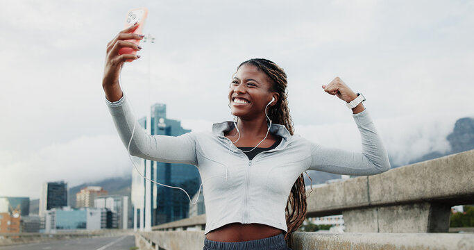 Exercise, selfie and black woman in city with win, cardio workout or smile with music. Fist pump, earphones or runner celebrate for wellness, sports and playlist outdoor with fitness photography
