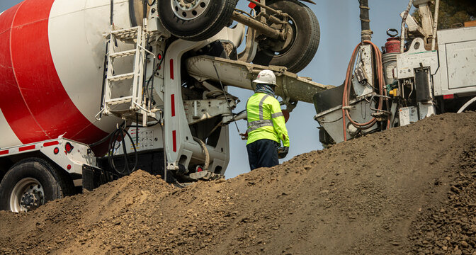 Looking up at a construction worker near a cement truck delivering cement