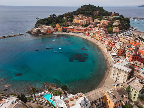 Aerial view of the Baia del Silenzio with its turquoise waters and colorful historic buildings along the sandy beach in Sestri Levante, Liguria, Italy.