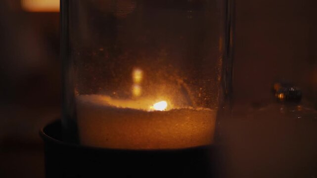 Close Up of candle burning in glass vase, the wax is low from extended usage.
