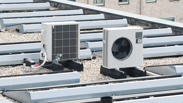 Aerial view of air conditioning units and heat pumps installed on a gravel rooftop with modern skylights in the Nobelhorst district Almere, Flevoland, Netherlands.