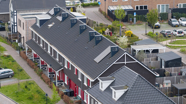 Aerial view of modern terraced houses in the Nobelhorst neighborhood with solar panels and heat pump units on dark roofs in Almere, Flevoland, Netherlands.