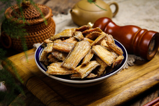 Crispy fried hairtail fish pieces in bowl on rustic wooden table