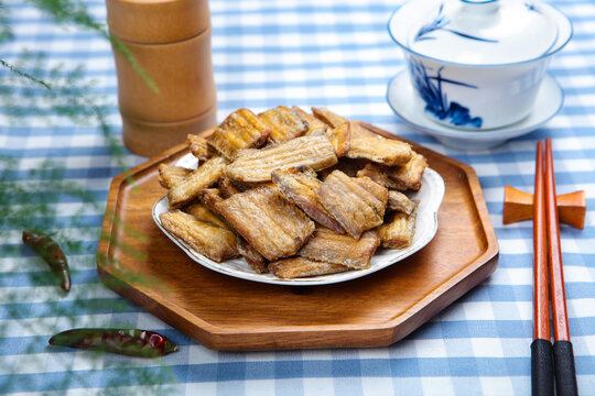 Crispy fried hairtail fish crackers on plate with chopsticks and tea set