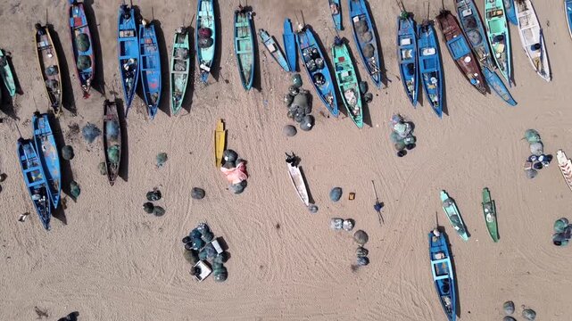 Aerial top view of fishing boats lined on sandy beach with waves in Kovalam Kerala India