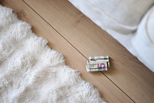 Money on the floor next to a rug in a living room