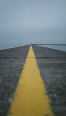 Fototapeta premium Lighthouse journey along a weathered pier evokes serene coastal travel mood and distant misty horizon