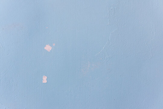 An old wall surface with peeling paint and deepening cracks
