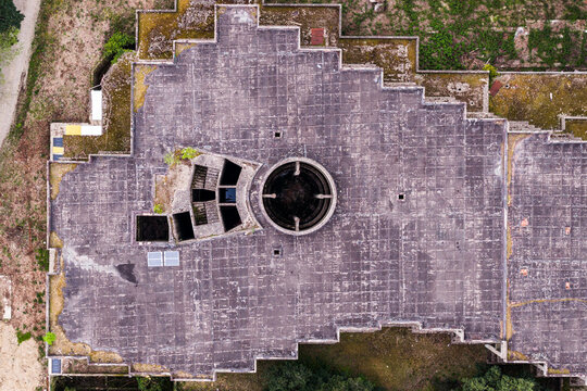 Aerial view of the geometric concrete roof of a modern architectural structure with a circular central opening and stepped edges in Reggello, Tuscany, Italy.