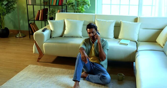Indian young man frustrated because of call fail while making a call using smartphone in busy network in modern Indian home showing distress and annoyance during an important conversation