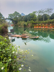 Fototapeta premium Rustic wooden raft with cormorant floats on calm green river.