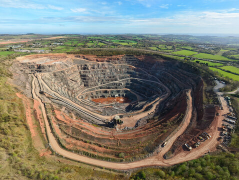 Aerial view of Old Cliffe Hill quarry showing the deep terraced excavation pit and surrounding green countryside under a blue sky in Stanton under Bardon, England, United Kingdom.