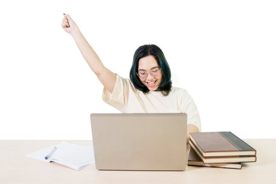 Excited Asian Student Celebrating Success While Working on Laptop at Desk