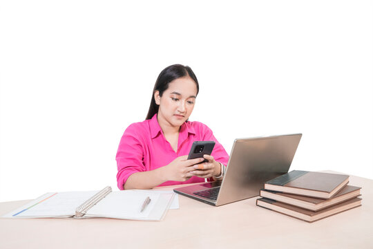 Smiling Asian Female Student in Pink Shirt Working on Laptop with Books and Notebook on Desk