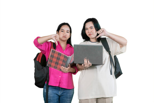 Disappointed Female University Students Giving Thumbs Down with Laptop and Notebook