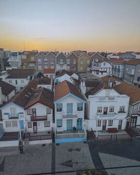 Aerial view of colorful striped beach huts and rooftops in sunset, Costa Nova, Aveiro, Portugal.