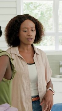 Vertical video: Handing mint pack in kitchen, mom in jeans helping kids zipping packs for school