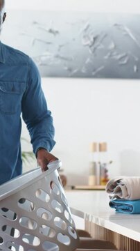 Vertical video: Entering kitchen dad in denim with basket as child in pink top running to high-five