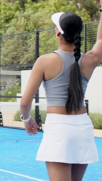 Vertical video: Ball coming, woman in gray top lunging with paddle to return shot on blue court