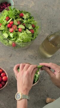 Vertical video: Reaching basil bowl, adult hands tearing basil and garnishing salad at home, watch