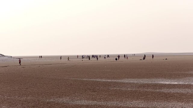 Group of people enjoying leisure time on a vast muddy beach, socotra island