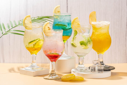 sunrise in doha, clasic mojito, sparkling wardah, blue oasis, and sparkling mamara, served in clear glass and on a white coaster with a brown base and a gray background 
