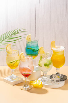 sunrise in doha, clasic mojito, sparkling wardah, blue oasis, and sparkling mamara, served in clear glass and on a white coaster with a brown base and a gray background 