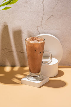 sparkling wardah non alcoholic drink served in a glass on a cream colored table with a white stone coaster, a wooden patterned background, and leaves palm as decoration.