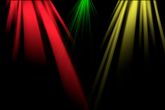 Focos de escenario con rayos de luces de colores rojo, verde y amarillo sobre fondo negro.