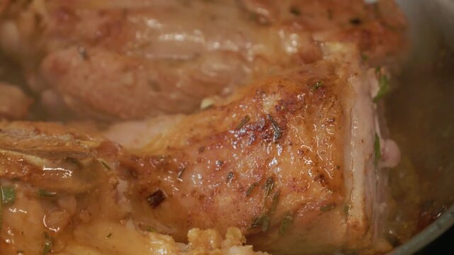 Lamb pieces cook in a pan with heat. The meat sizzles and gives off steam as it cooks. This process shows the preparation of lamb for a meal.