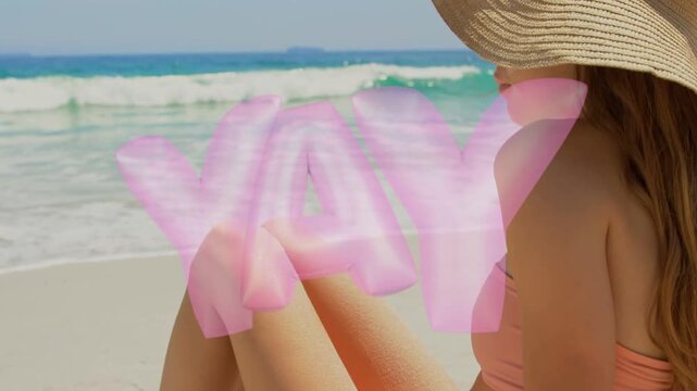 Camera panning, woman sitting on shore, pink YAY appearing, hat settling, shades lifting for travel