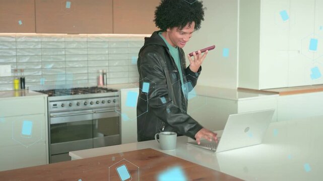 Man speaking into phone, typing on laptop at island, blue tech graphics checking metrics on screen