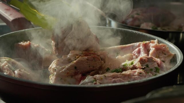 Lamb pieces sizzle in a pan on the stove. Steam rises as the meat cooks, filling the kitchen with rich flavors and aromas. A simple cooking process unfolds.
