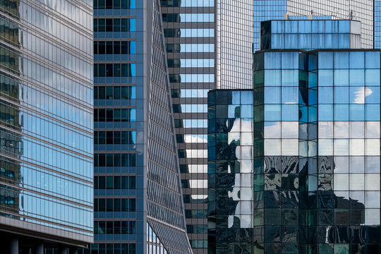 Layered modern architecture with glass office skyscraper building facade reflection in Paris France featuring overlapping volumes geometric window grid clean lines and sky