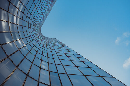 Minimal upward view of modern architecture as glass office skyscraper building facade shows reflection in Paris France with blue sky clean lines and copy space
