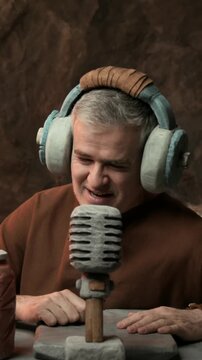 Prehistoric live streamer and radio host working in the studio, he is wearing headphones and speaking into the microphone