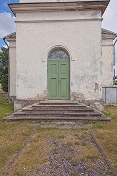 Green arched front double door on a peeling plaster wall in summer, Muhu, Estonia, Europe.