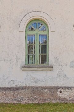 Old arched window with a green-painted wooden frame set into a rustic wall, Muhu, Estonia, Europe.