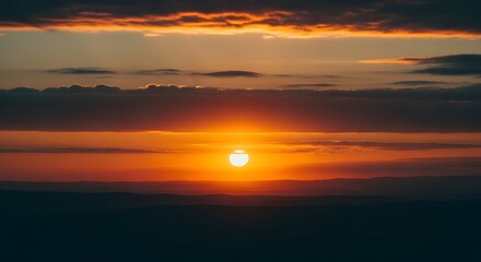 Obraz premium Dramatic sunset over a dark mountain range with a bright sun and layered clouds
