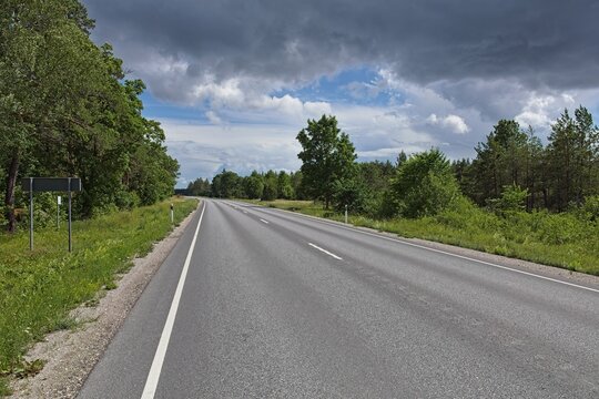 Kuivastu - Kuressaare asphalt road road in rural landscape in cloudy summer weather, Muhu, Estonia, Europe.