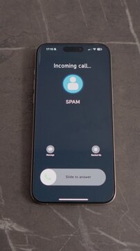 Vertical Screen: A smartphone is resting on a marble table while displaying an incoming call marked as spam. The screen shows options to message or decline the call.