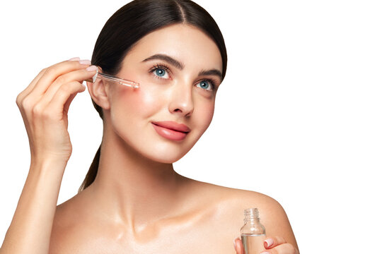 Young beautiful woman applying face serum with pipette. Cosmetic procedures for facial skin care